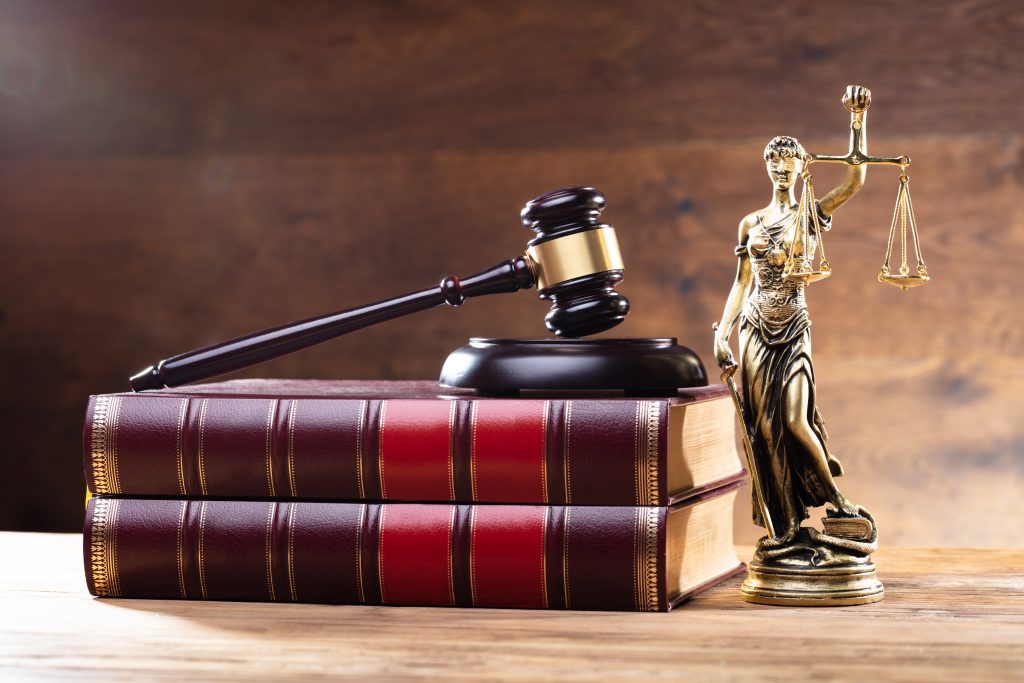 Judge&rsquo;s gavel, Lady Justice statue, and law books symbolizing legal system and justice.