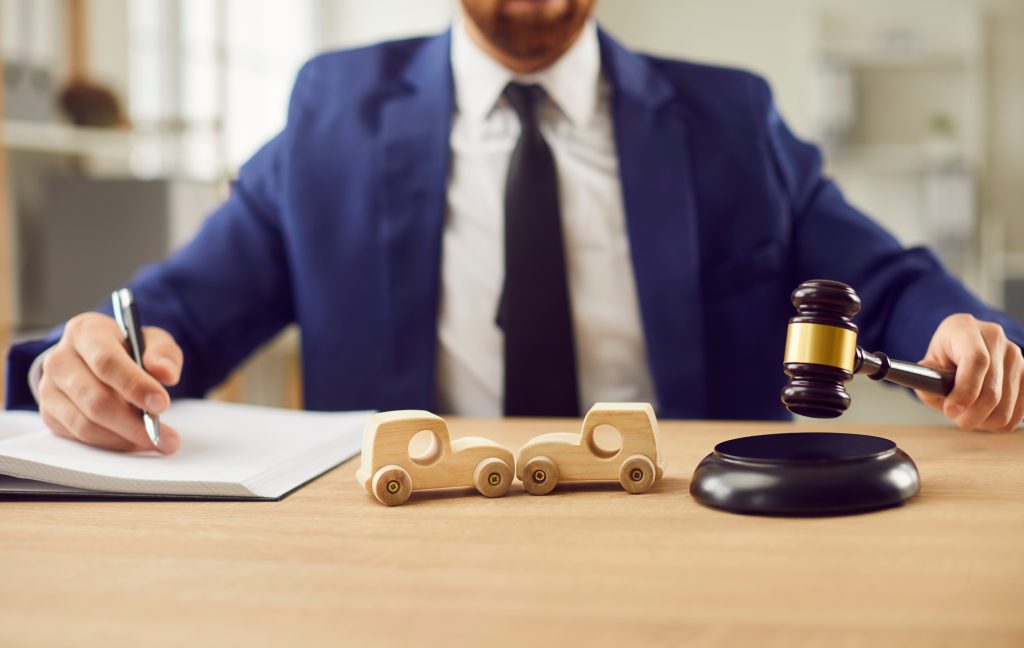 lawyer next to two wooden car models and a gavel next to it