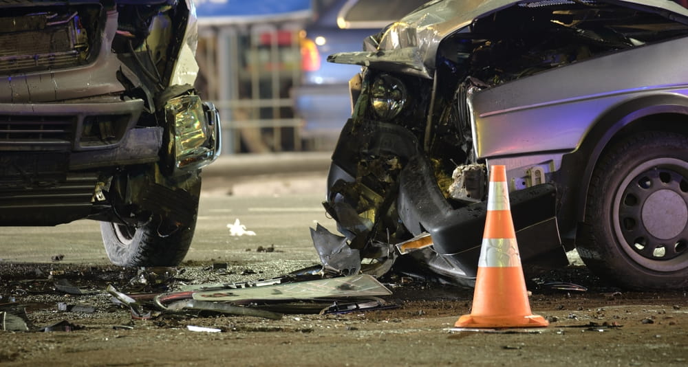 Two heavily damaged vehicles after a serious nighttime collision, illustrating major crash injuries and disputed insurance claims.