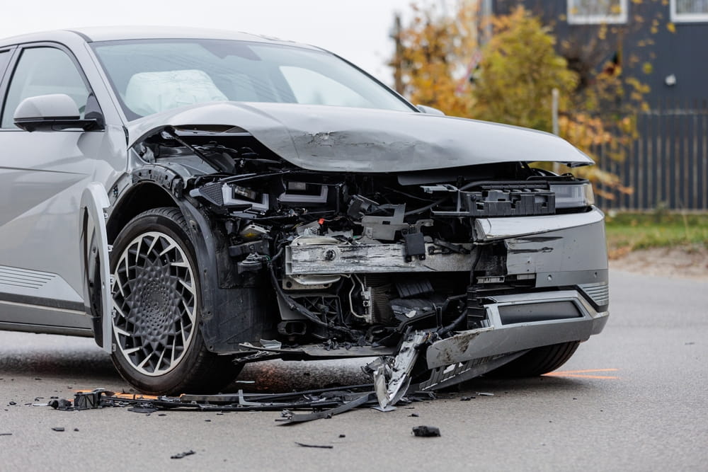 Car with extensive front-end damage after a collision, representing accident investigations and reopened injury claims.